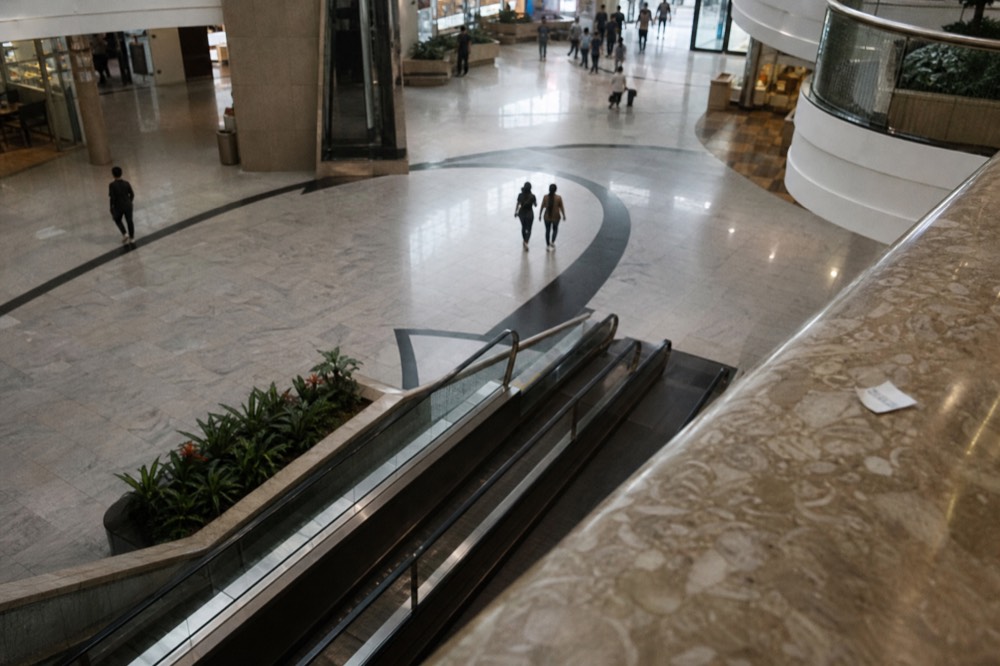 A wide mall atrium with escalators descending toward a basement entertainment floor, no text, no logos, no people
