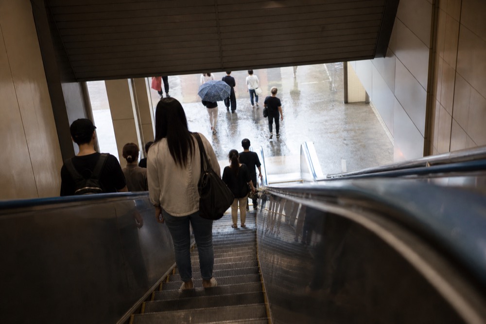 Escalator descending inside a shopping mall toward a basement food court, no text, no logos, no people.