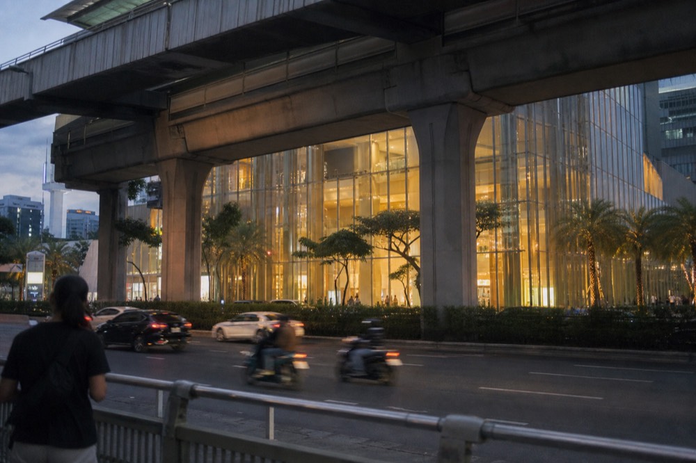 Evening exterior of Siam Paragon with the BTS Skytrain track overhead, no text, no logos, no people