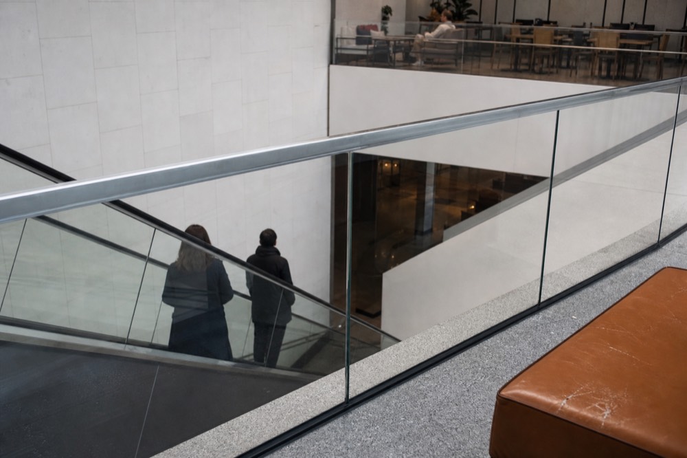 Downward escalator inside a shopping mall beside a seating area, no text, no logos, no people.