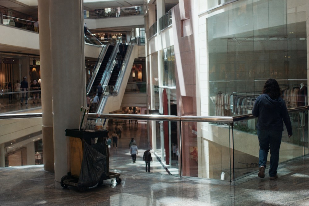 Wide mall atrium with escalators and shopfronts on multiple levels, no text, no logos, no people.